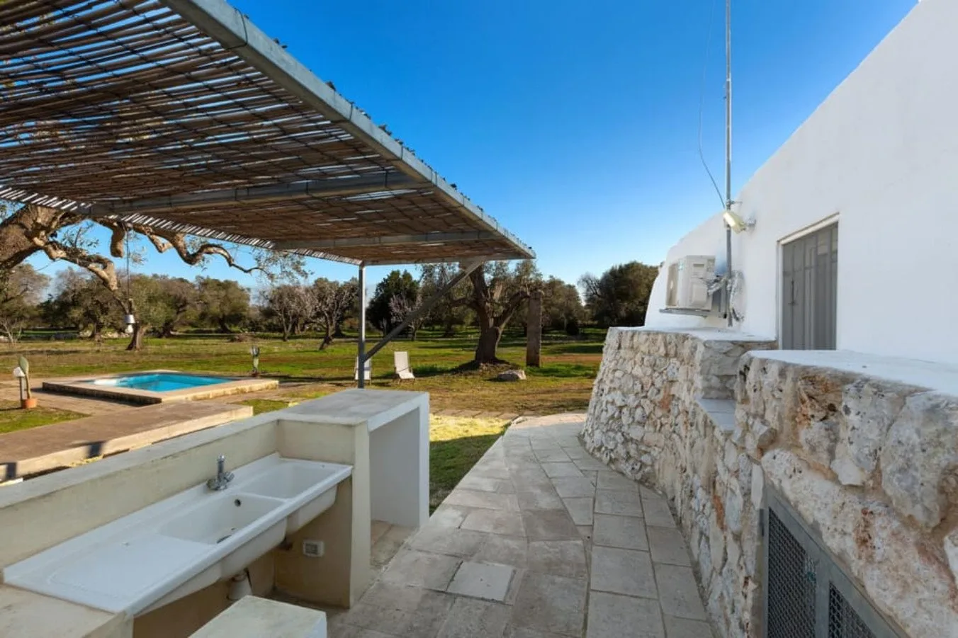 An outdoor patio beside a white building overlooks a pool and grassy yard.