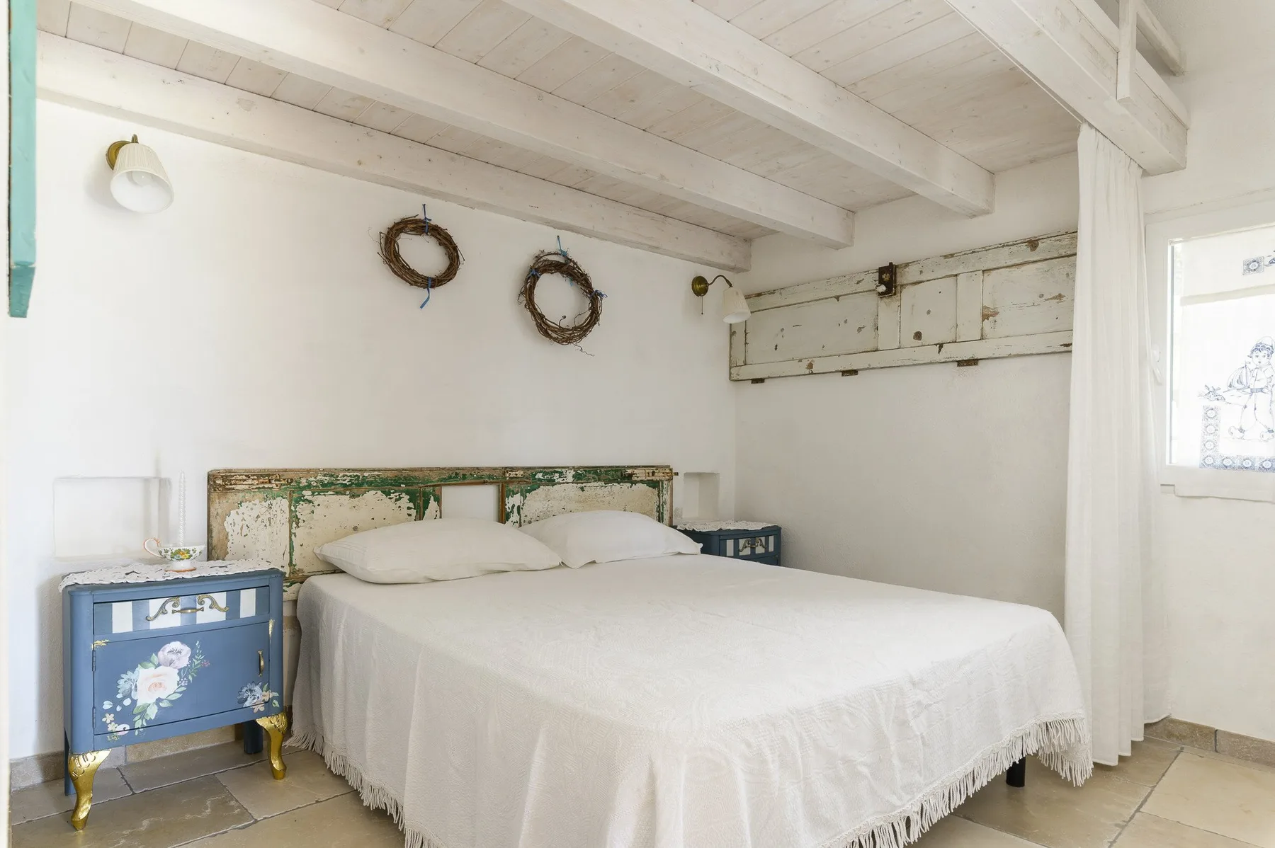 A bright bedroom with a large bed and blue bedside tables.