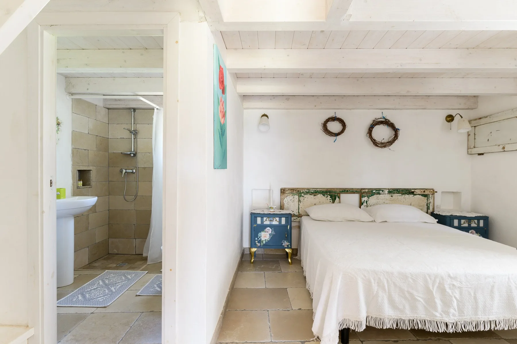 A bedroom with a double bed beside an open bathroom doorway.