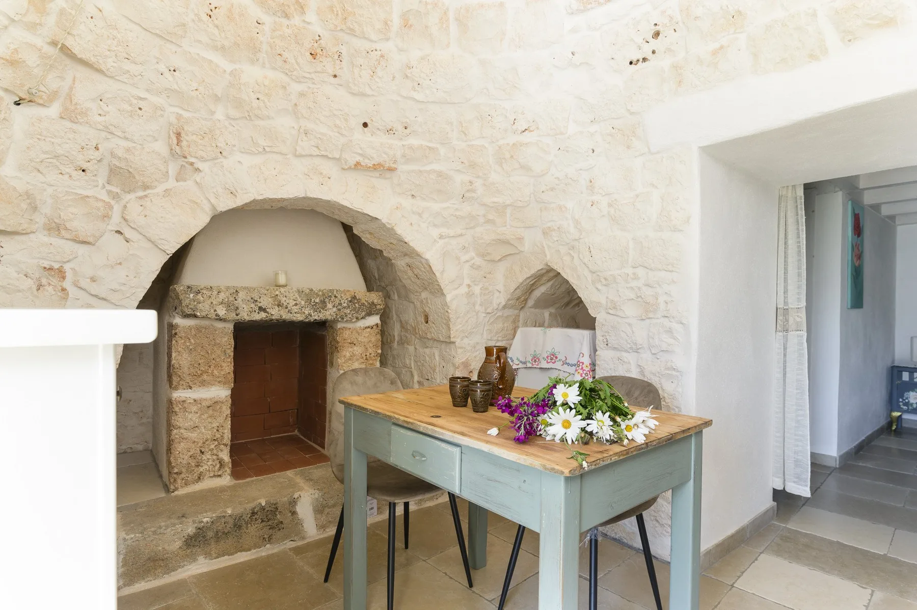 A stone interior with an arched fireplace and a table decorated with flowers.