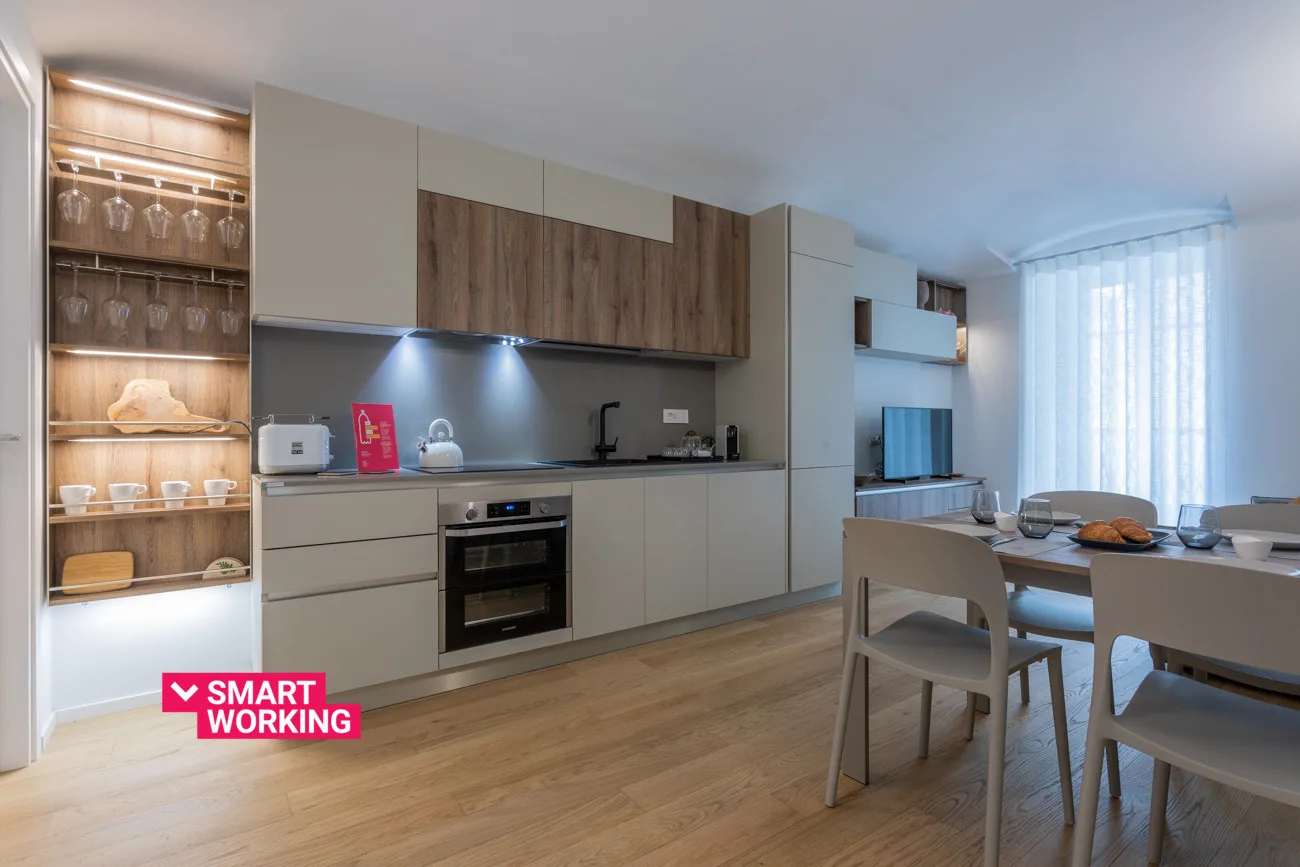 A modern kitchen opens onto a dining area with a table and chairs.
