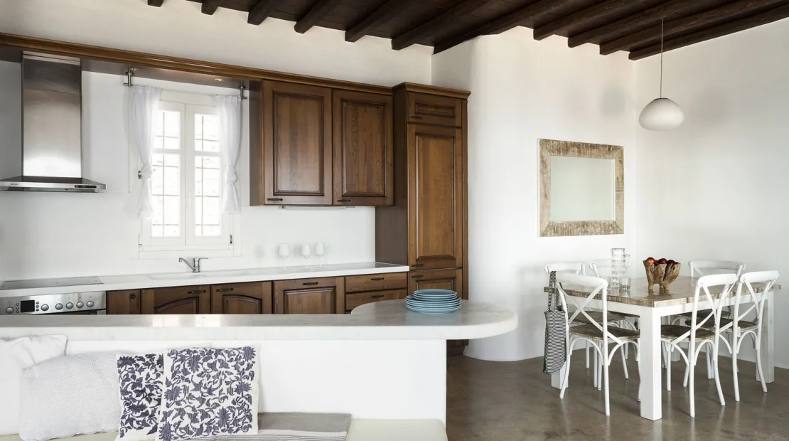 A kitchen and dining area with dark wood cabinetry and a table.