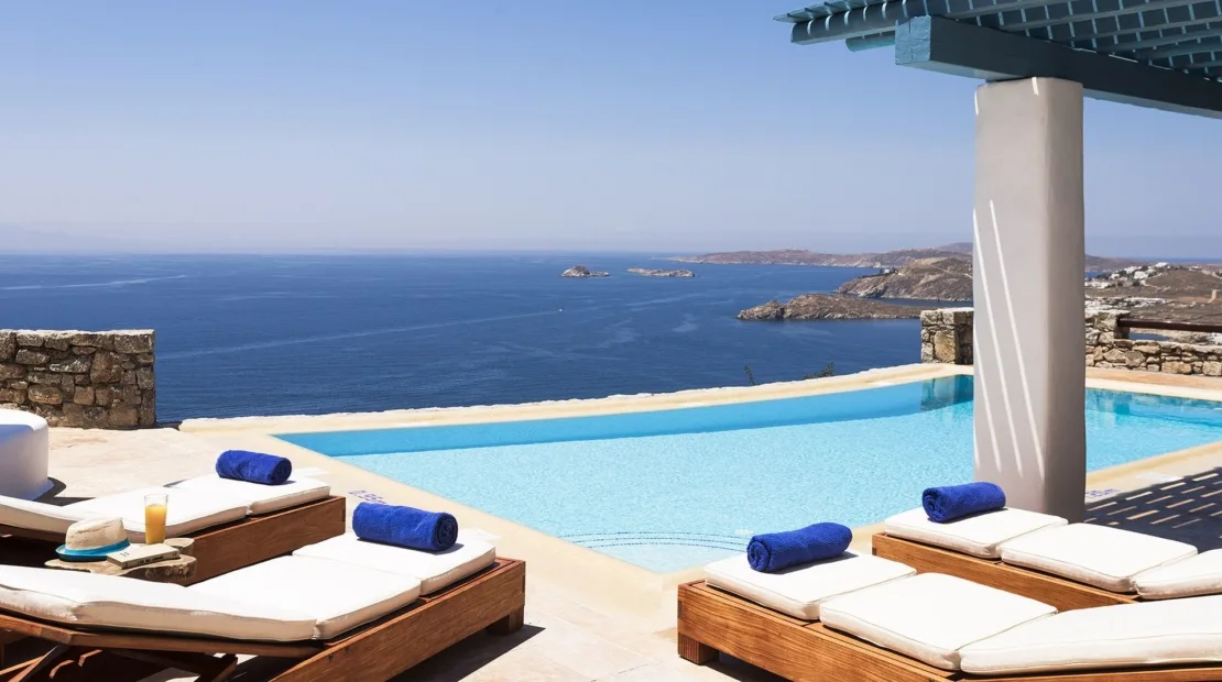 A swimming pool overlooks the sea, with lounge seating along the deck.