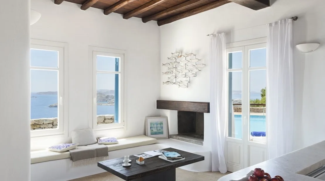 A bright living room has window-side seating and views of the sea.
