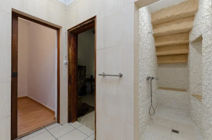 A tiled bathroom with a walk-in shower and two doorways.