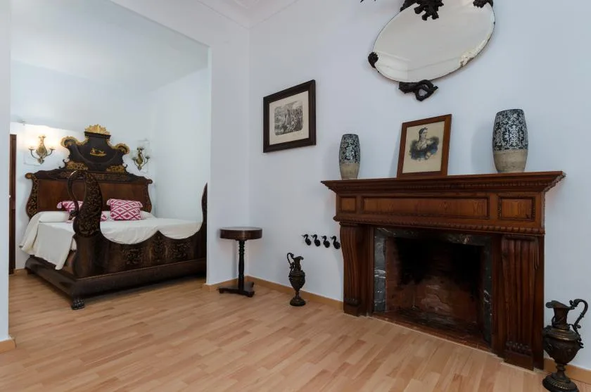 A bedroom with an ornate bed and a large fireplace.