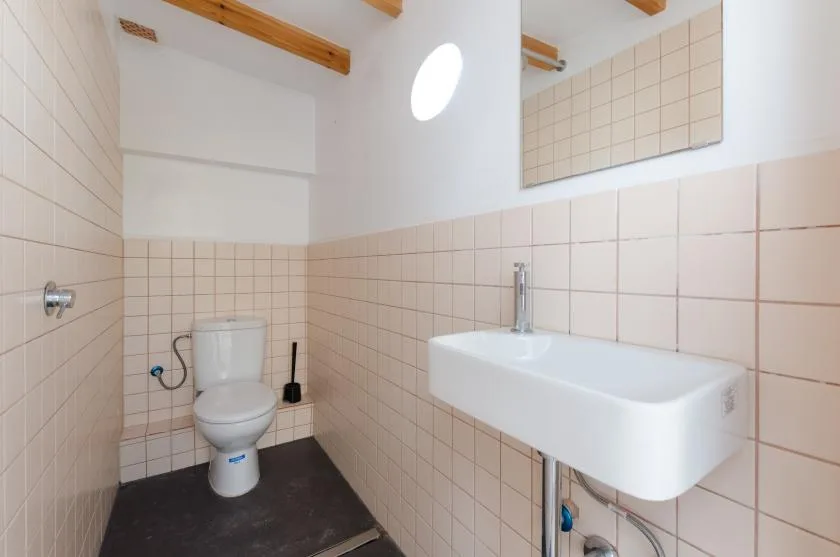 A tiled bathroom with a toilet and wall-mounted sink.