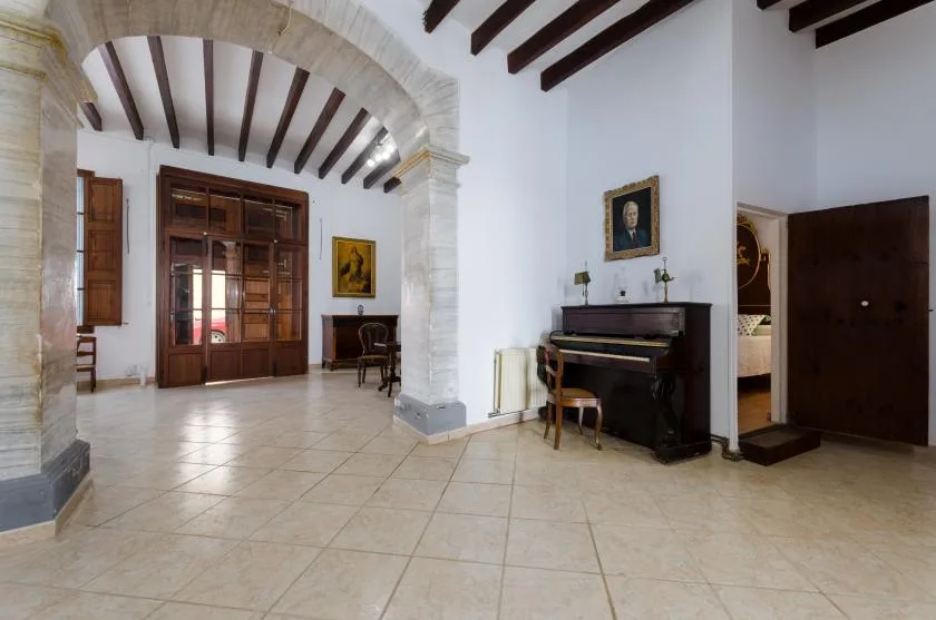 A spacious interior hall with a piano and dark wooden ceiling beams.