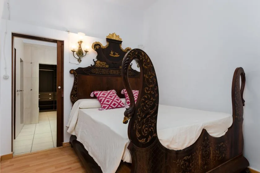 A bedroom with an ornate dark wooden bed and white bedding.
