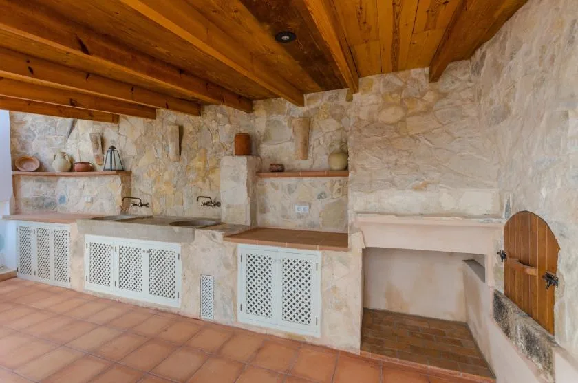 A rustic kitchen with stone counters, white cabinet doors, and a wooden ceiling.