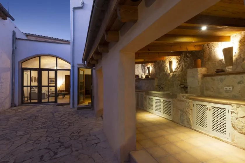 A stone courtyard beside a covered stone passage with warm wall lighting.