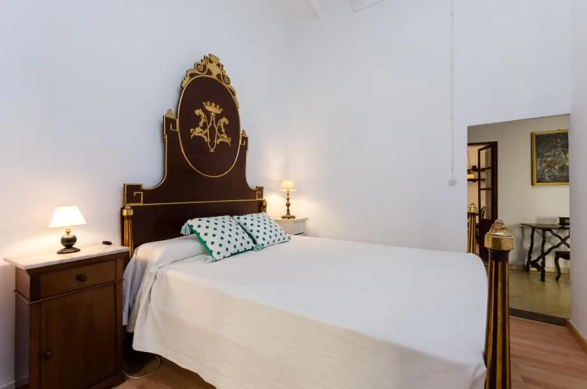A bedroom with a large bed, dark ornate headboard, and matching bedside tables.