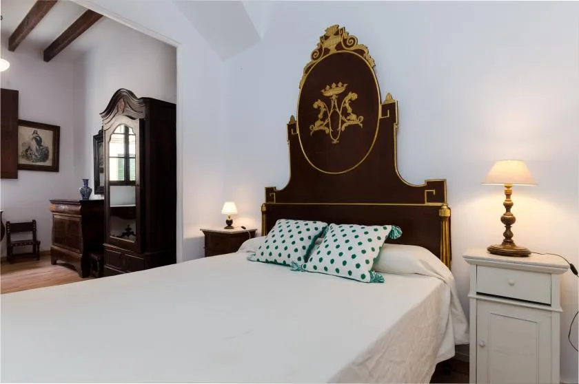 A bedroom with a large bed and an ornate dark headboard.