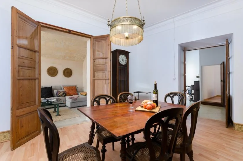 A dining room with a wooden table and chairs beneath a hanging light.