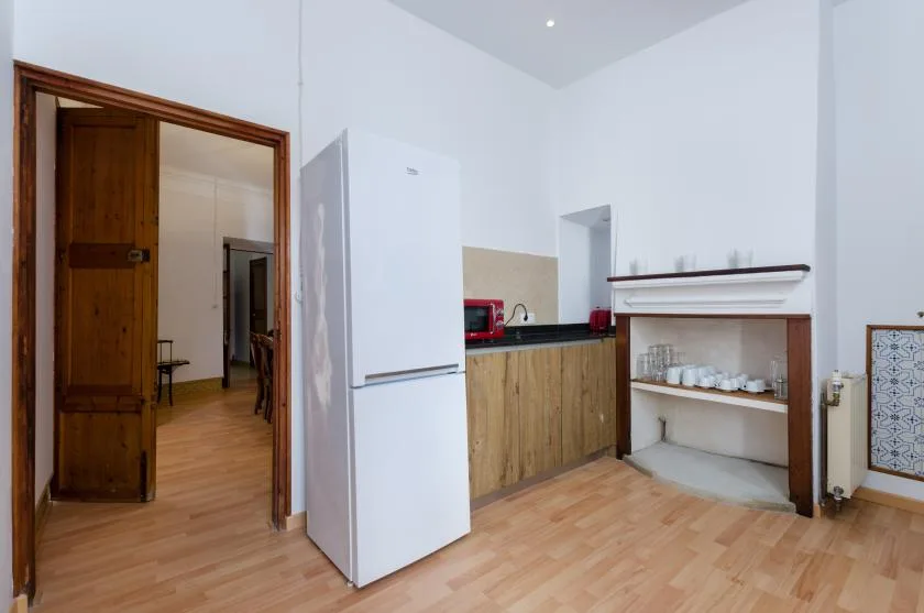 A bright kitchen with wood cabinets, a refrigerator, and open shelving.