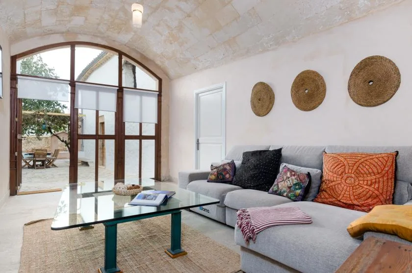 A bright living room with a sectional seating area and large arched glass doors.