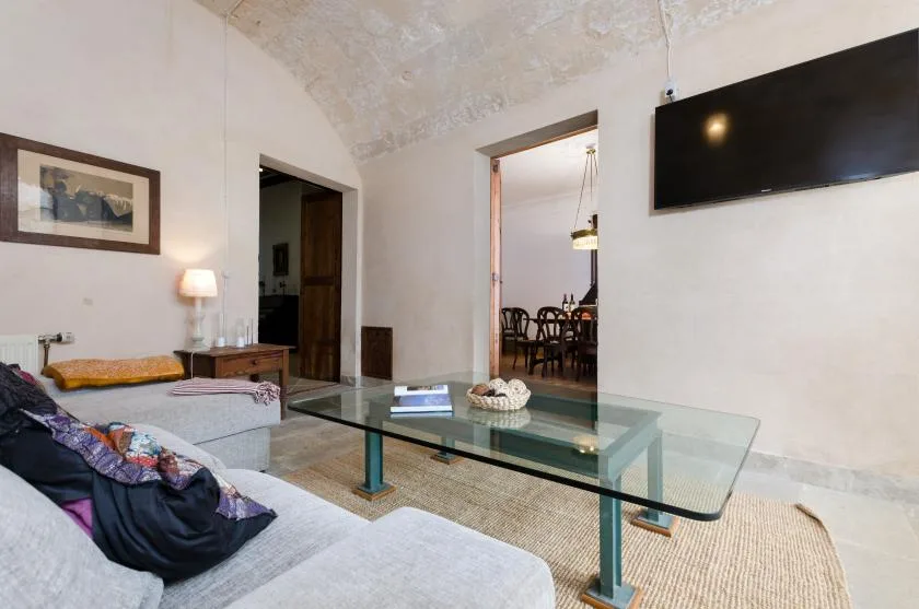 A living room with a glass coffee table and seating.