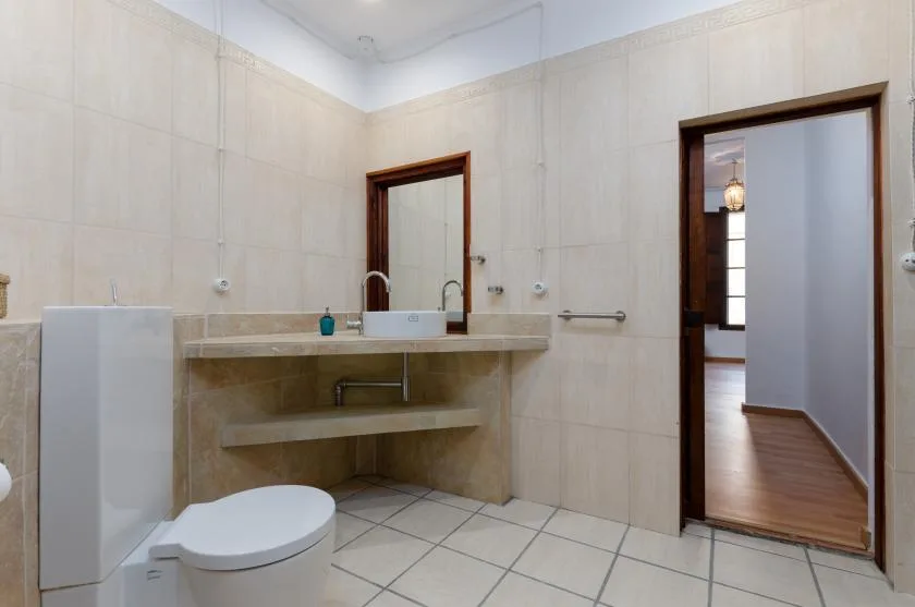 A tiled bathroom with a sink, toilet, and doorway to a hallway.