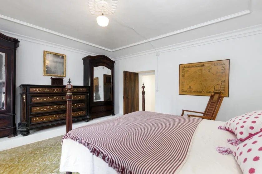 A bedroom with a large bed, dark wooden furniture, and framed artwork.