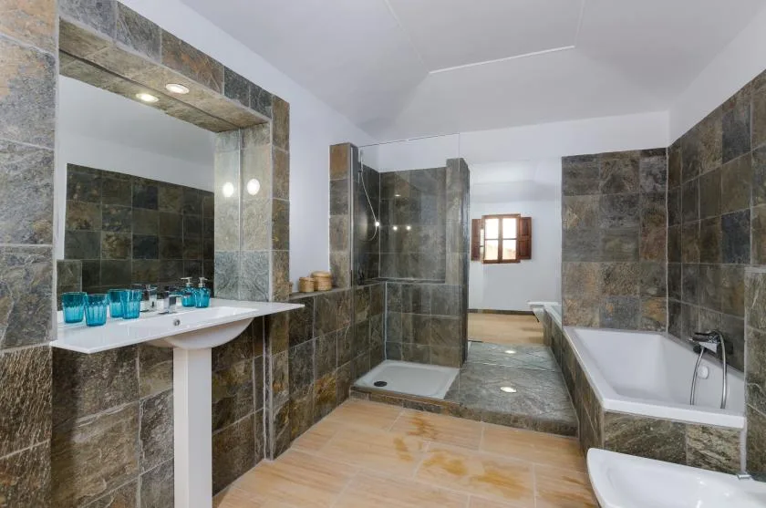 A tiled bathroom with a sink, shower, and bathtub.