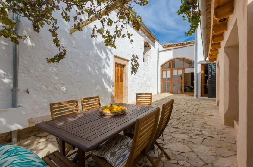 A stone-paved courtyard with an outdoor dining table beside white walls.