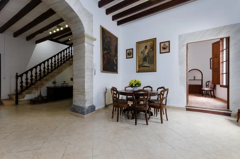 A dining area with a wooden table and chairs sits beside a staircase.