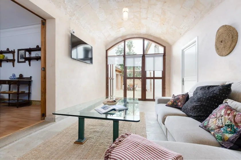 A bright living room with a glass coffee table and arched windows.