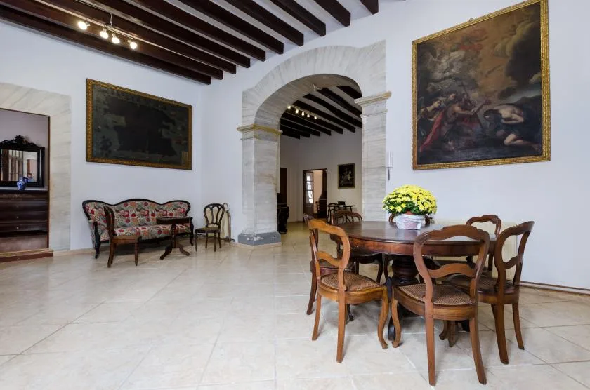 A dining room with a wooden table and chairs beneath a large stone archway.