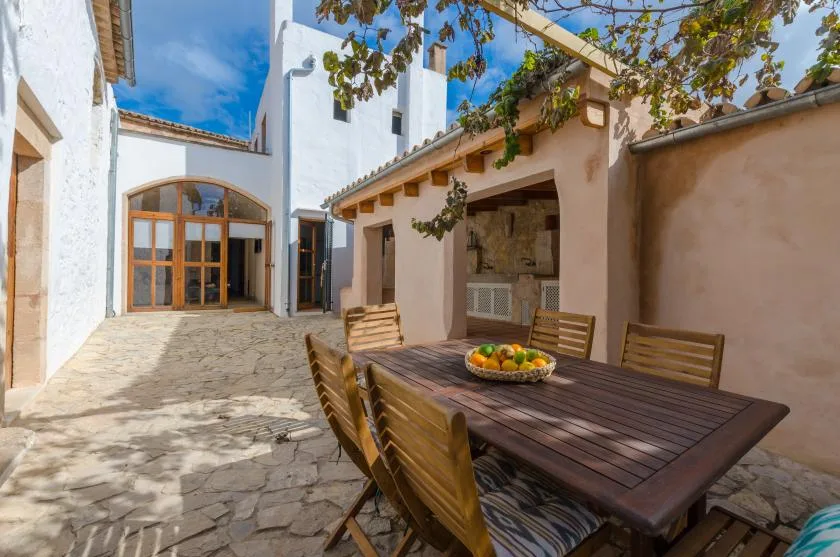 A stone-paved courtyard has outdoor seating beside a shaded dining area.