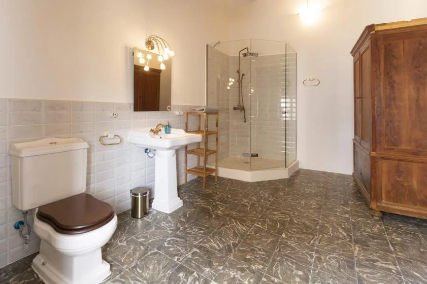 A bathroom with a sink, toilet, glass shower, and wooden cabinet.