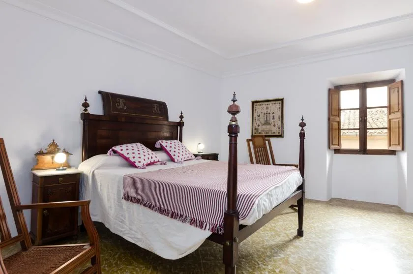 A bedroom with a wooden bed, patterned bedding, and a window.