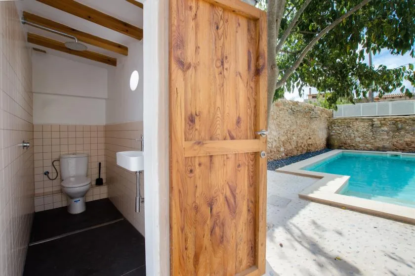 A bathroom opens onto a swimming pool through a wooden door.