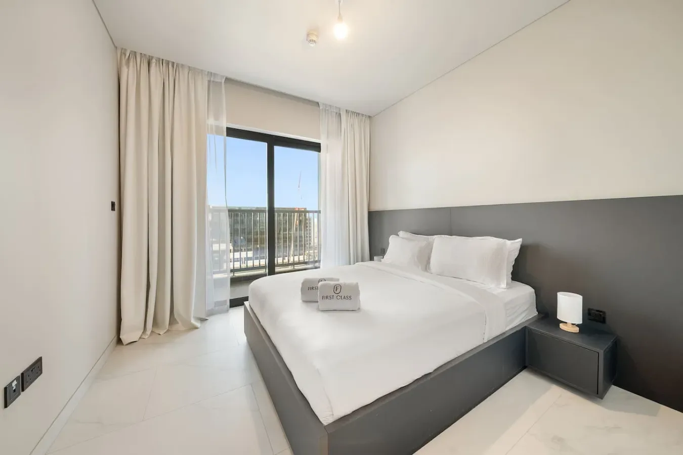 Un dormitorio luminoso con una cama bien hecha junto a una ventana grande.