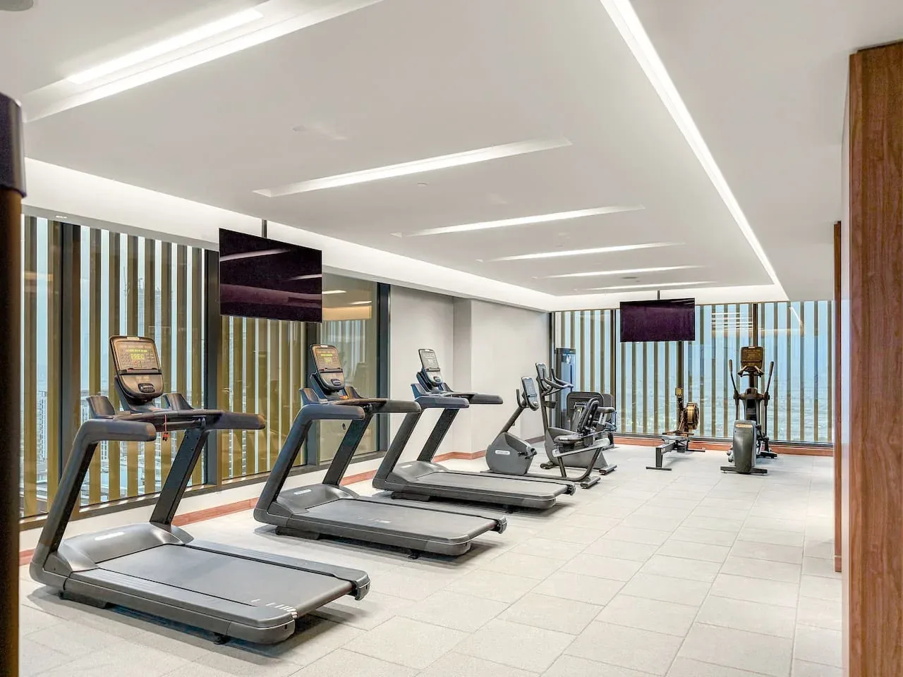Un gimnasio luminoso con cintas de correr y otros equipos de ejercicio.