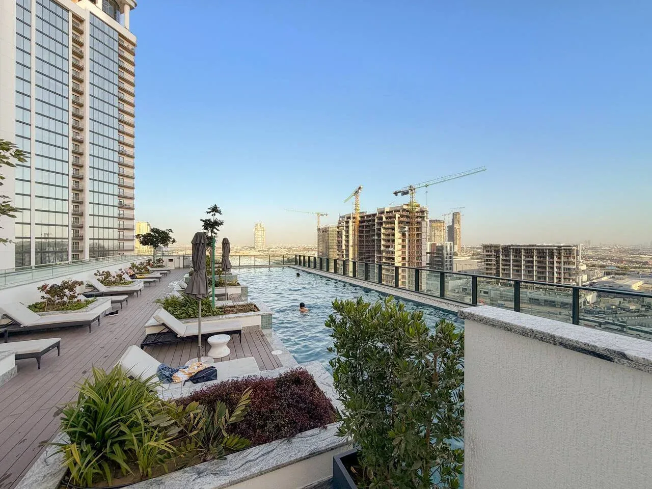 Una terraza con piscina en la azotea, asientos y vistas a edificios cercanos.