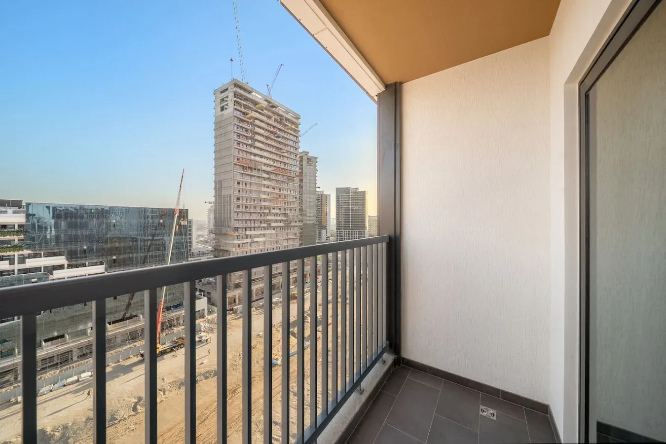 Un balcón estrecho da a edificios cercanos y zonas de construcción.