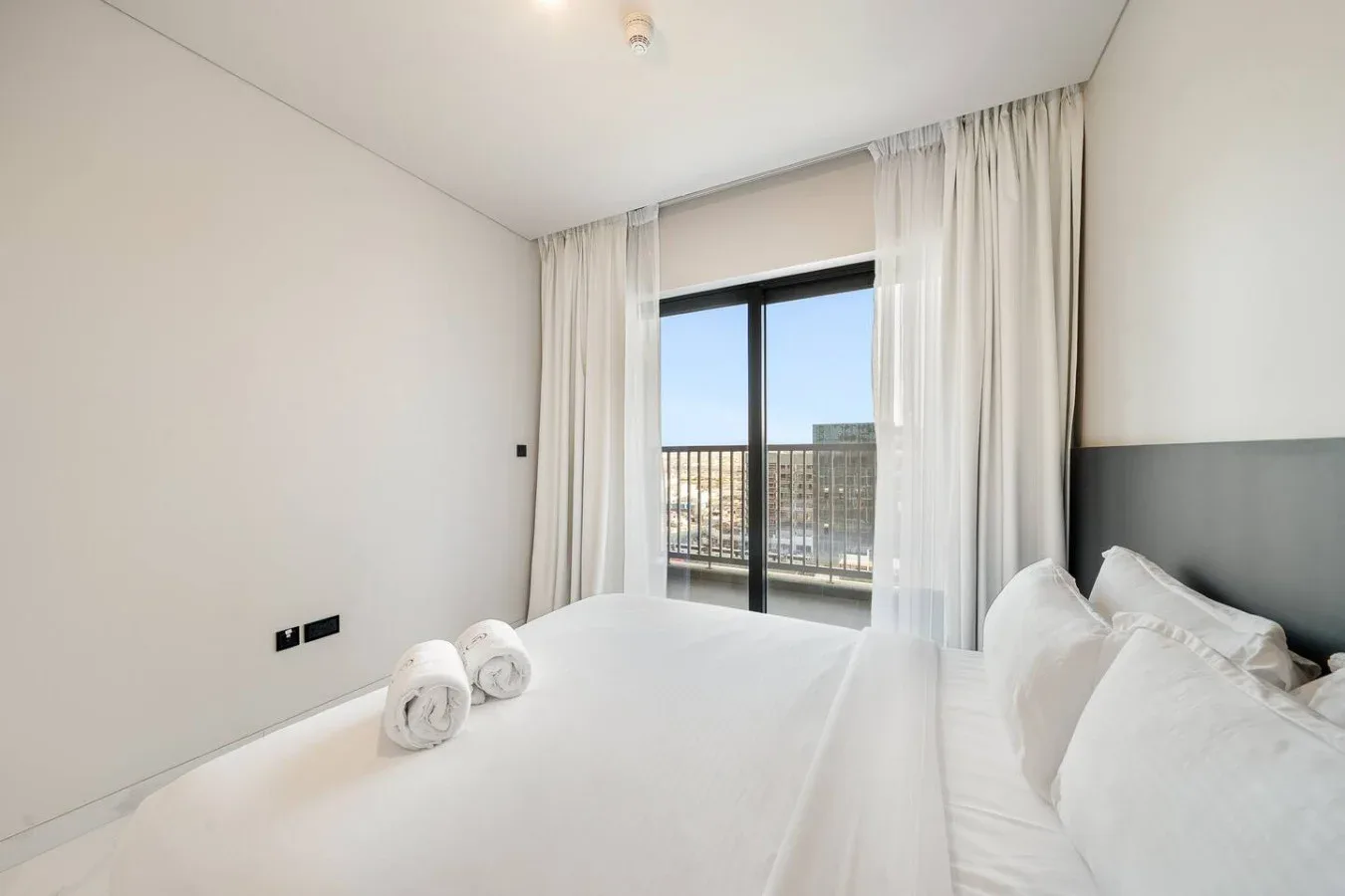 Un dormitorio luminoso con ropa de cama blanca y una ventana grande.