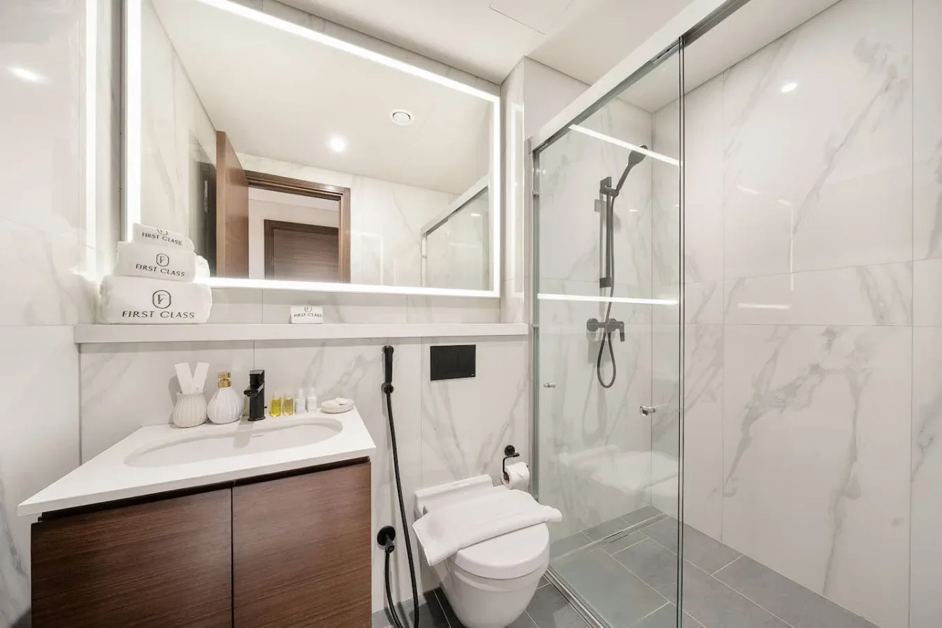 Un baño luminoso con lavabo, inodoro y ducha de vidrio.
