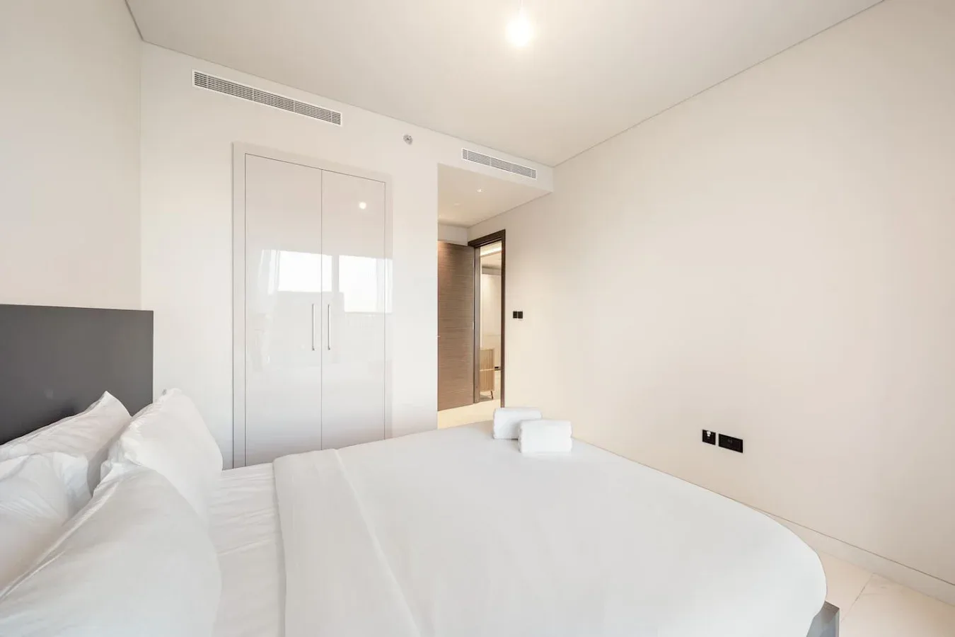 Un dormitorio luminoso con una cama bien tendida y un armario empotrado.