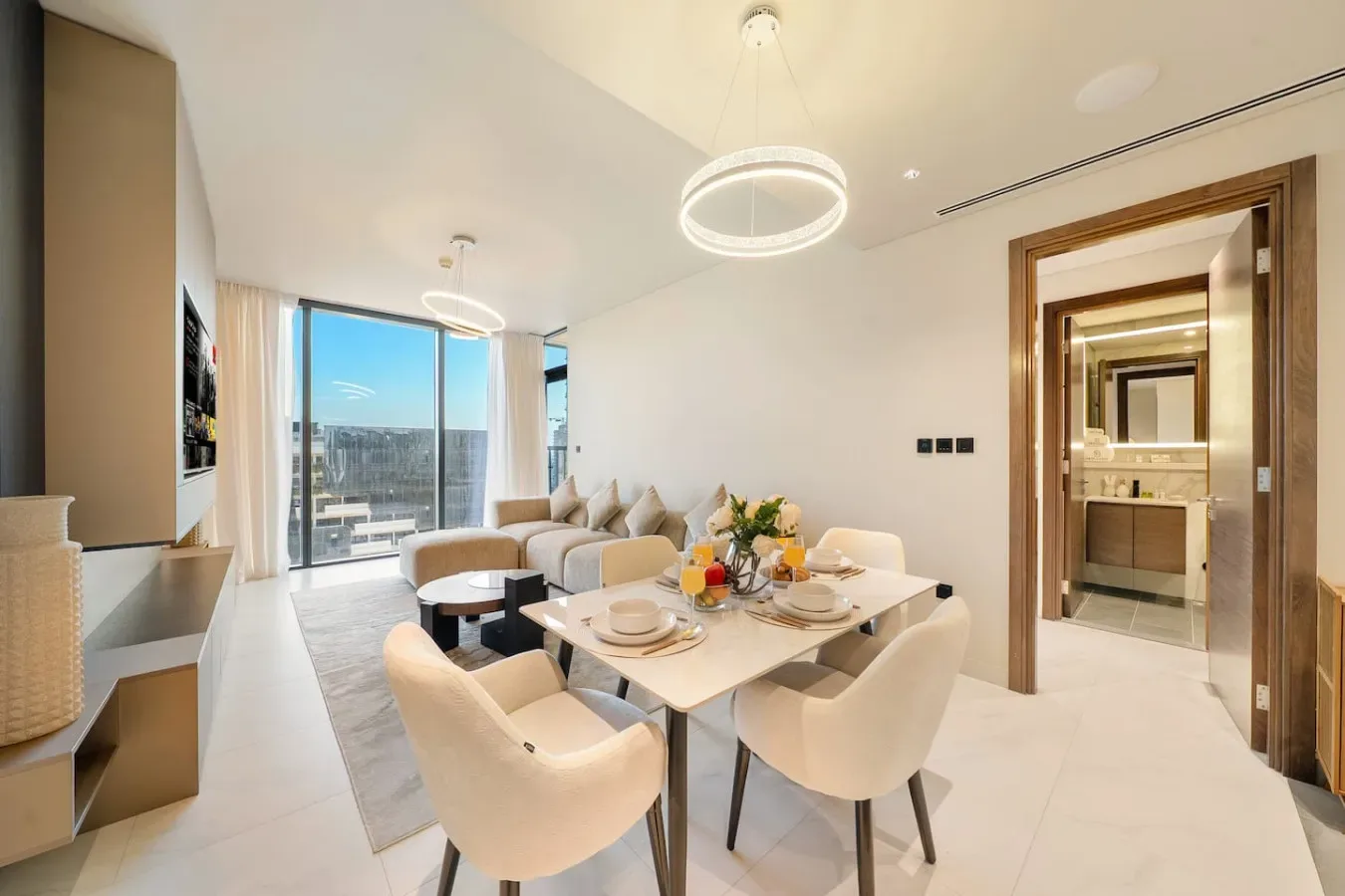 Una luminosa zona de comedor y estar con una mesa junto a grandes ventanales.