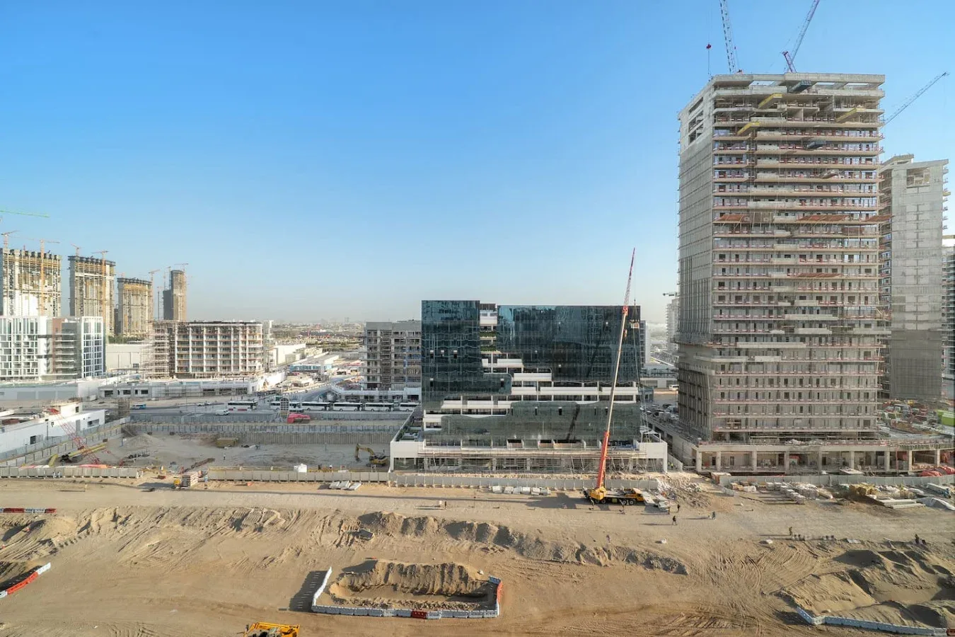 Una obra de construcción con varios edificios altos sin terminar bajo un cielo despejado.