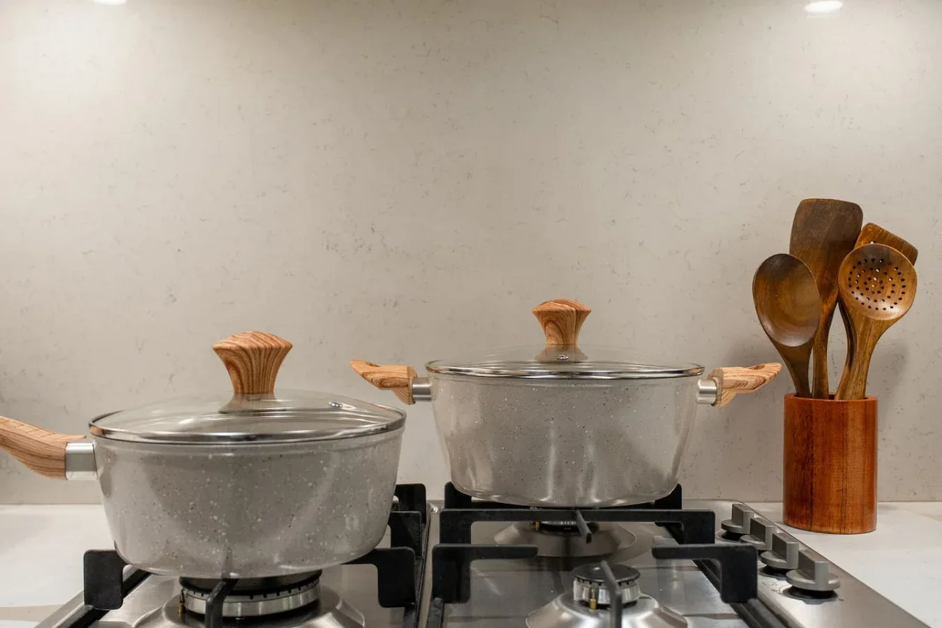 Una estufa de cocina con dos ollas y un recipiente para utensilios de madera.