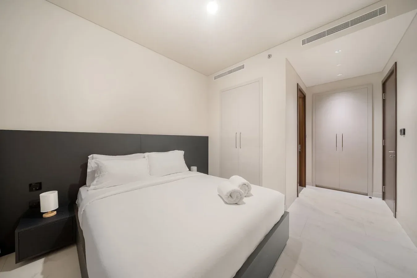 Un dormitorio luminoso con una cama bien tendida y armarios empotrados.