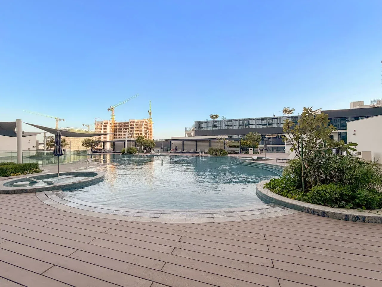Una piscina exterior curva está junto a una amplia terraza pavimentada.