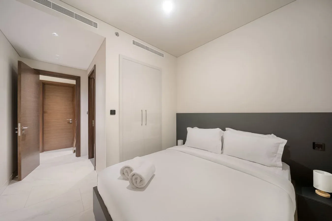 Un dormitorio luminoso con una cama bien arreglada y ropa de cama blanca.