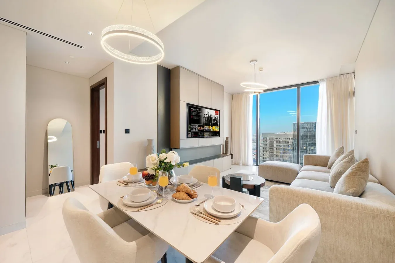 Un luminoso salón-comedor diáfano con grandes ventanales y la mesa puesta.