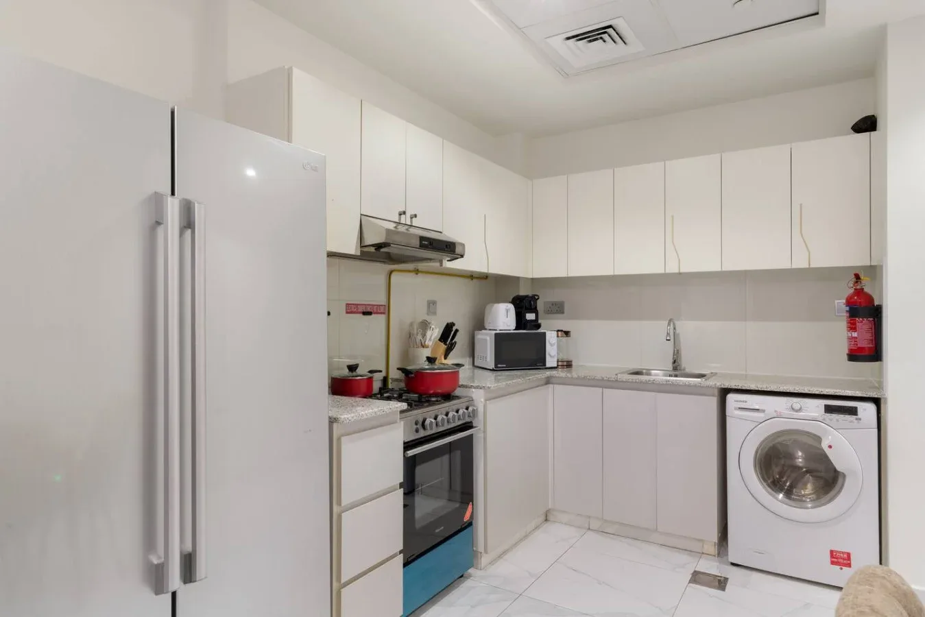 A bright kitchen with white cabinets, a refrigerator, and a washing machine.