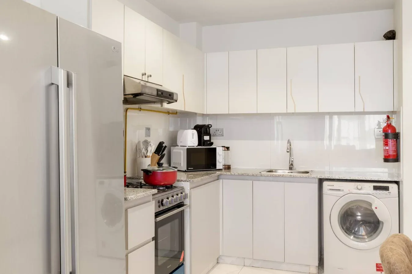 A bright kitchen with white cabinets, a refrigerator, and a washing machine.