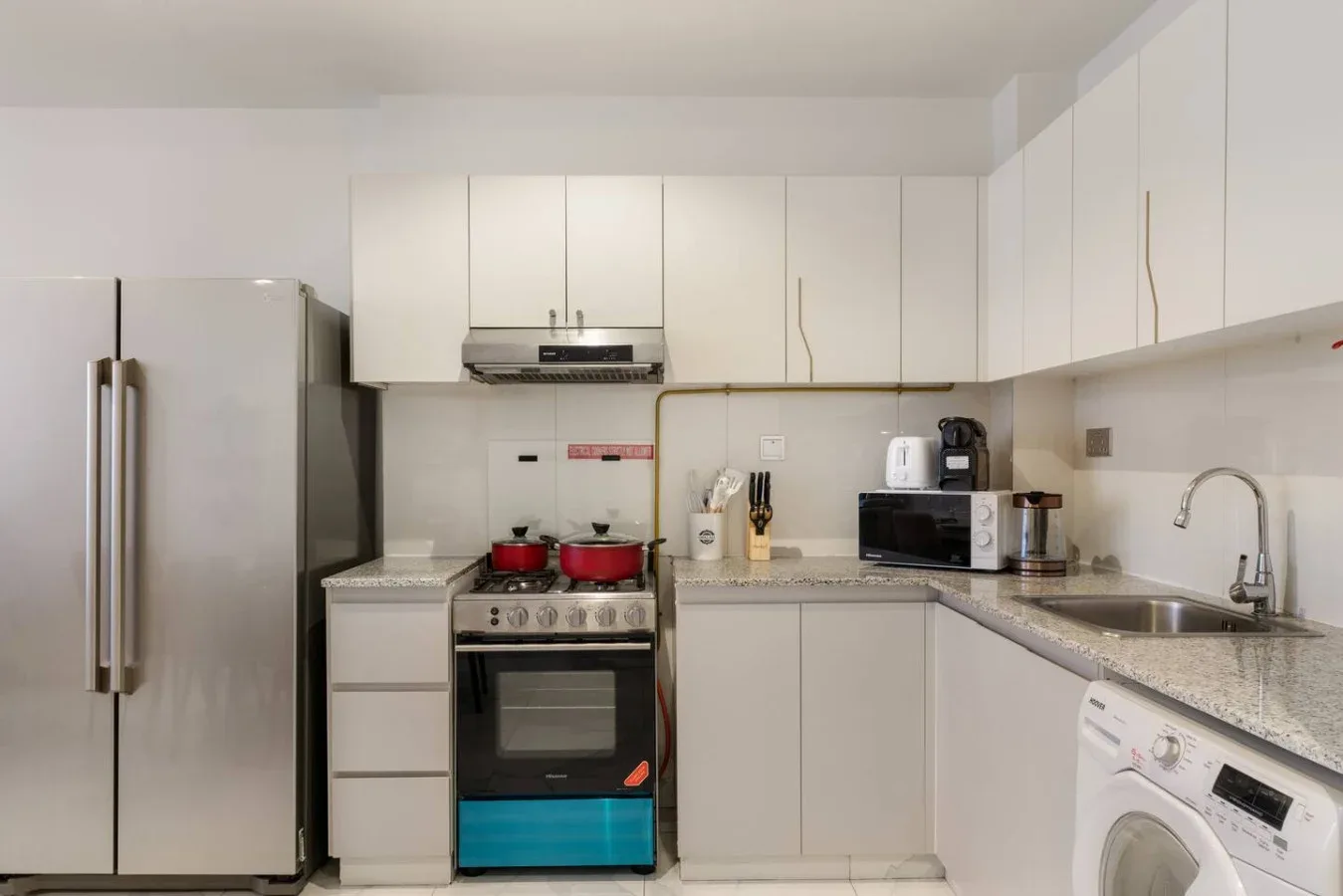A bright kitchen with white cabinets, a refrigerator, and a stove.