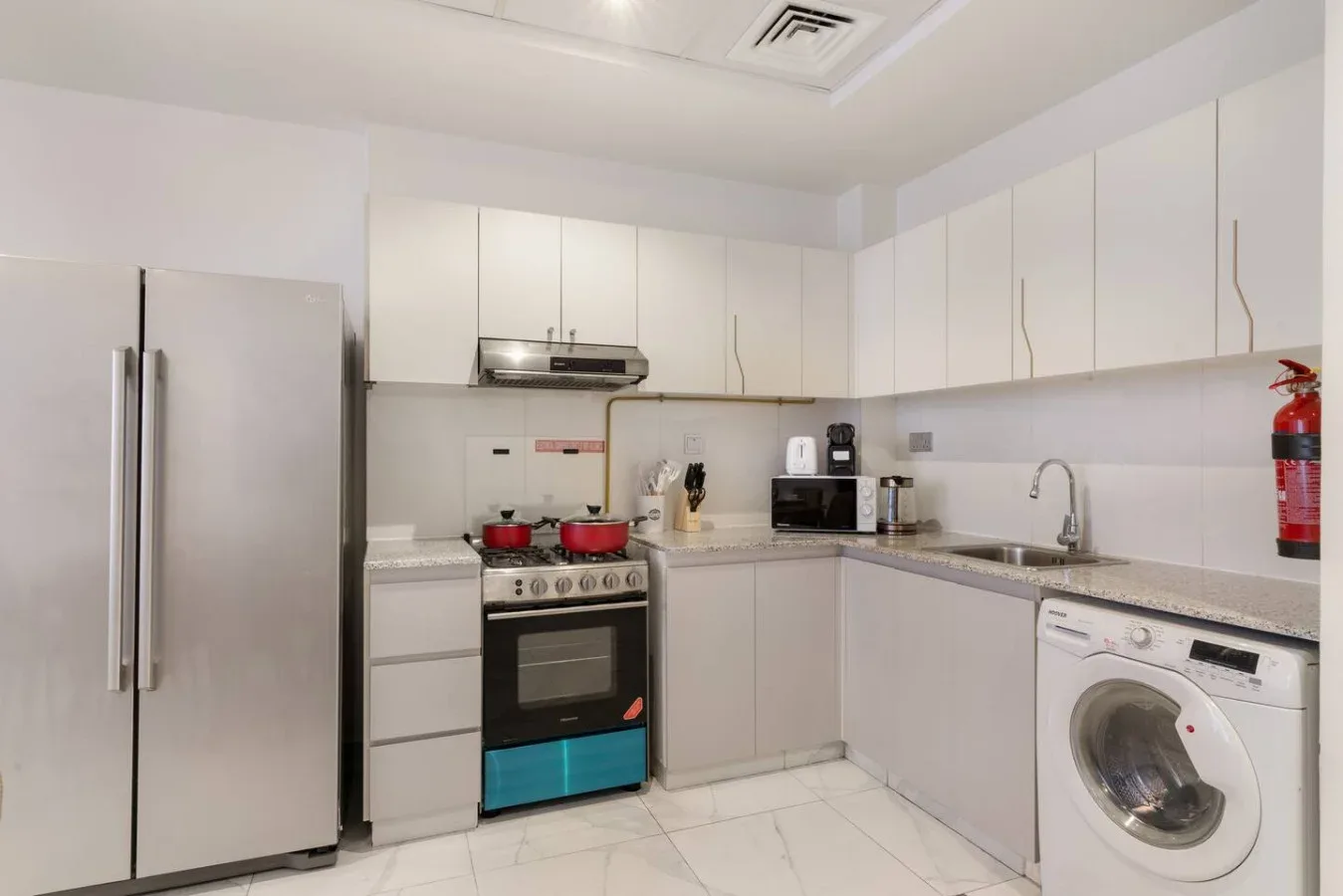 A bright kitchen with white cabinets, a stove, and a washing machine.